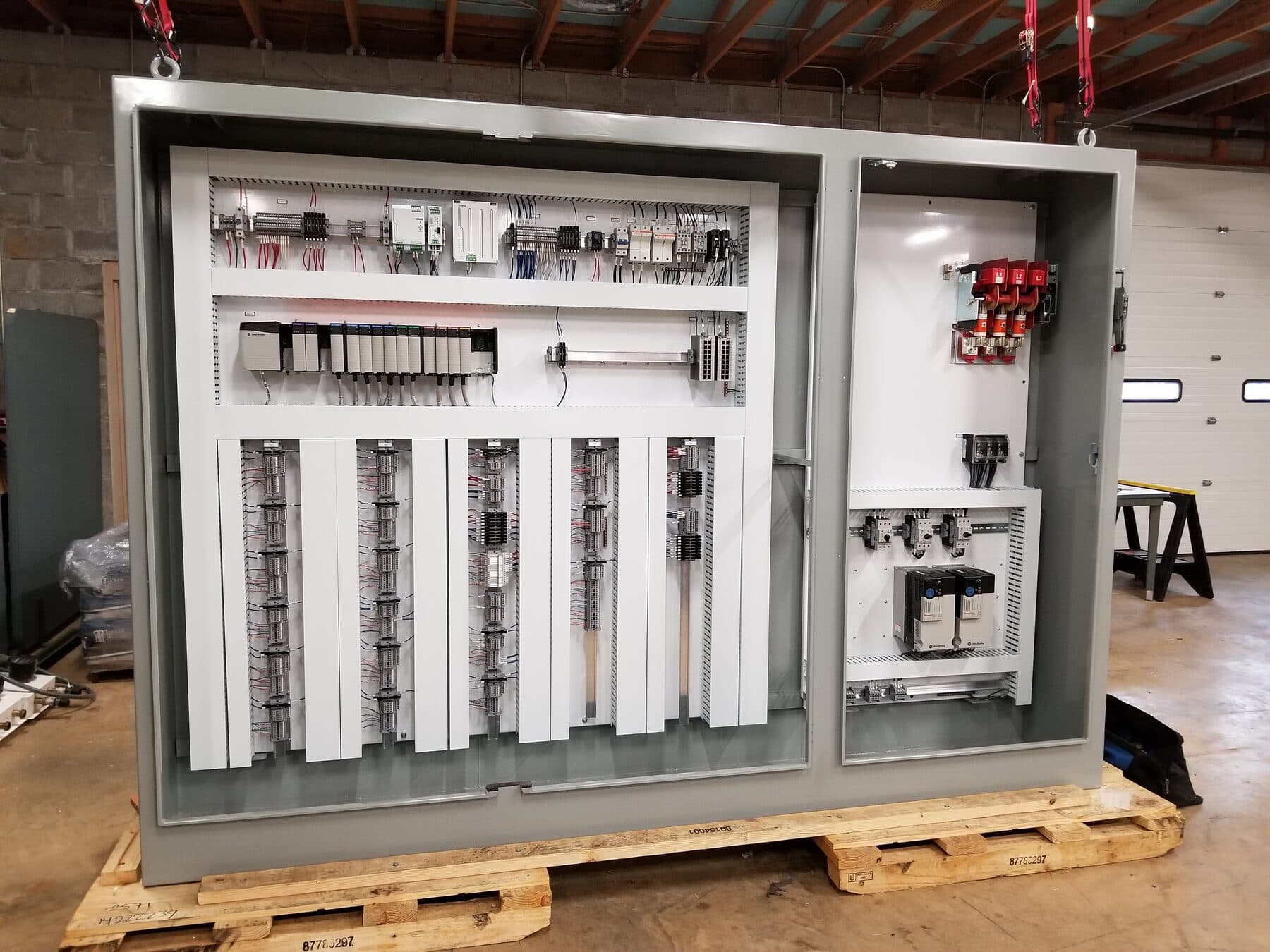 Two-section industrial control panel with an Allen-Bradley ControlLogix PLC rack, wireway and terminal block fields, PowerFlex variable frequency drives, and a fused disconnect, staged on a pallet.